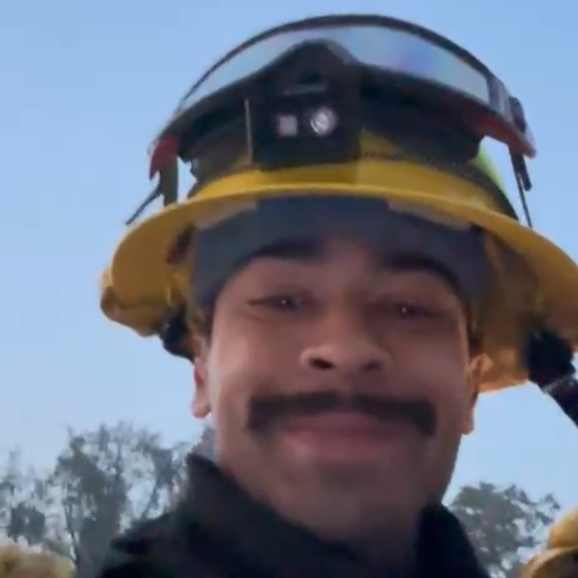 Person wearing a yellow helmet with a clear visor against a blue sky.
